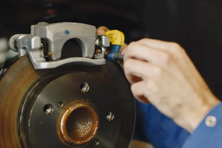 Close-up of a mechanic inspecting a car brake disc and caliper