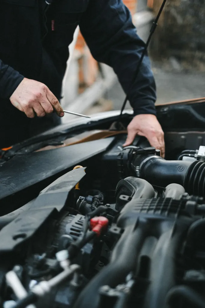 Mechanic checking components in a car engine bay