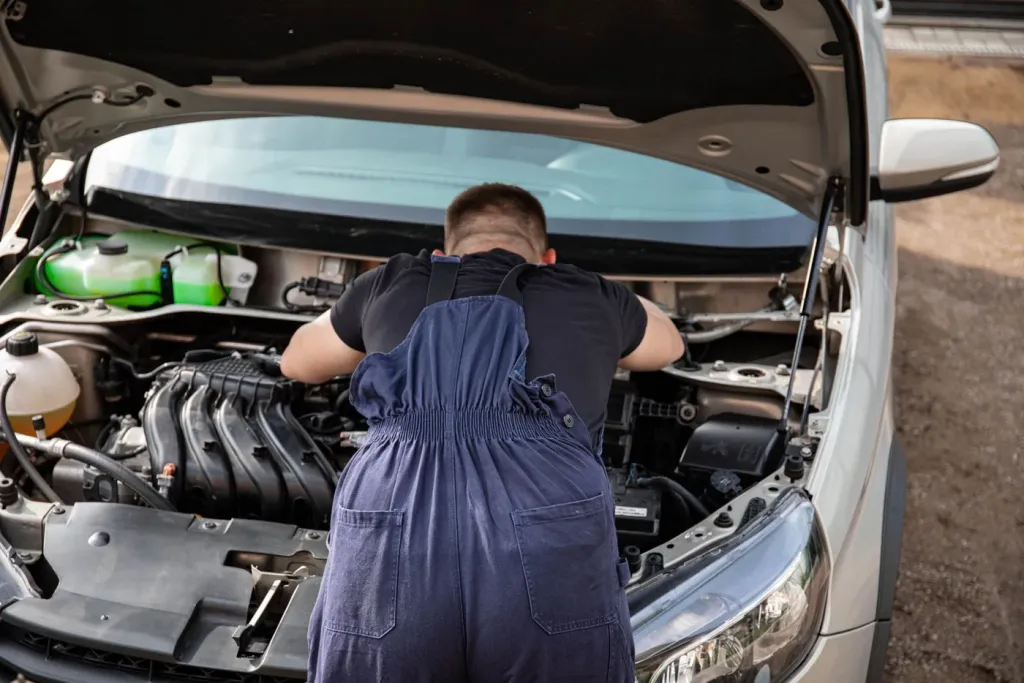 Mechanic carrying out maintenance under an open car bonnet